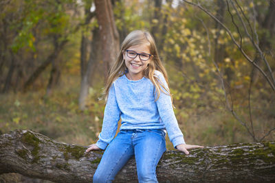 Smiling young woman standing against trees in forest