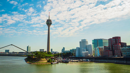 View of buildings at waterfront against cloudy sky over dusseldorf 