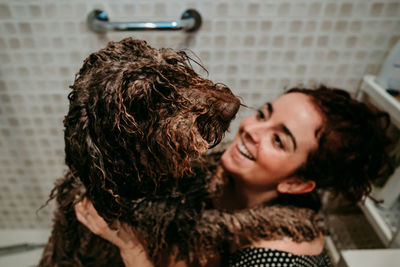 High angle view of smiling woman with dog in bathroom