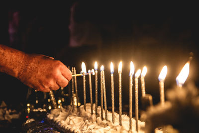 Close-up of hand igniting candle on cake in darkroom