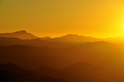 Scenic view of silhouette mountains against clear sky during sunset