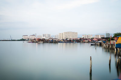 City buildings by river against sky