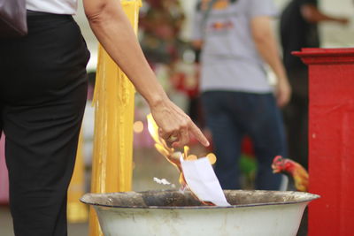 Midsection of woman throwing paper in fire