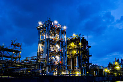 Low angle view of illuminated factory against sky at night