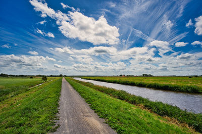 Road amidst field against sky