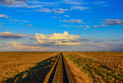 Railroad tracks on field against sky