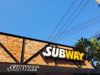 Low angle view of road sign against clear blue sky