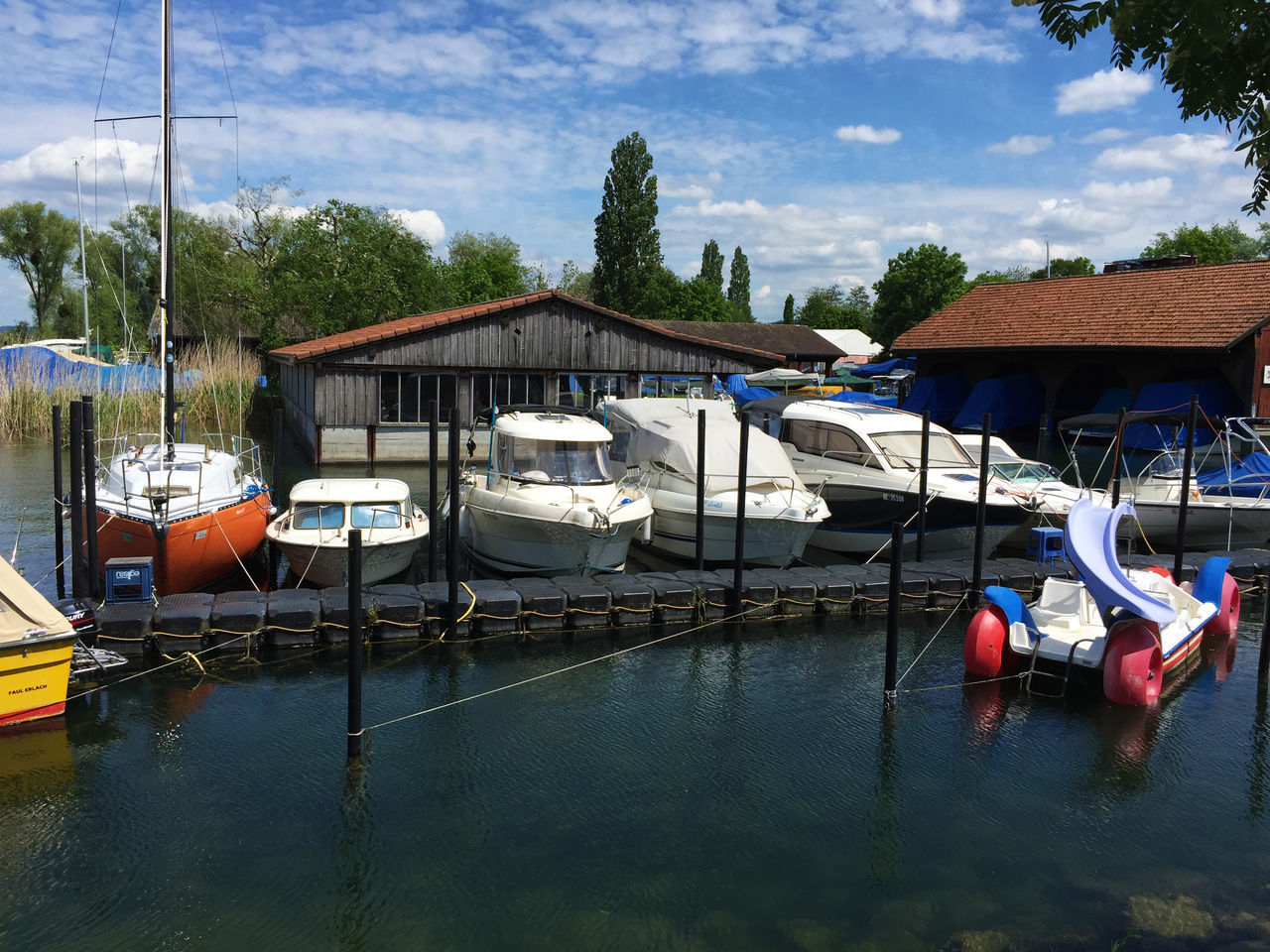 BOATS MOORED IN HARBOR AGAINST SKY