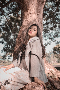 Low angle view of girl looking at tree trunk