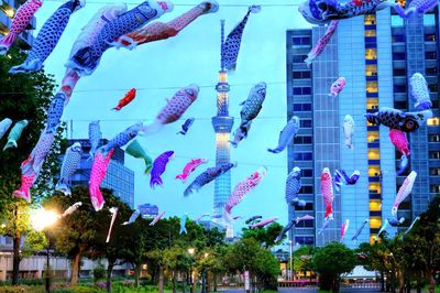 Multi colored flags hanging on tree in city