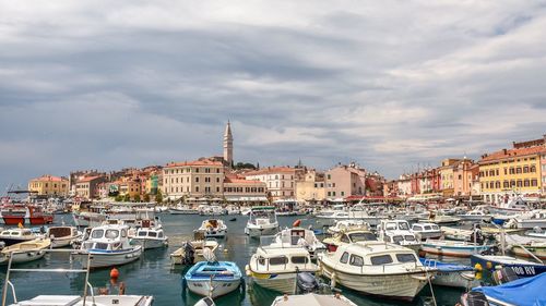 Boats in harbor against cloudy sky