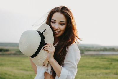 Young woman smiling while standing on field against sky