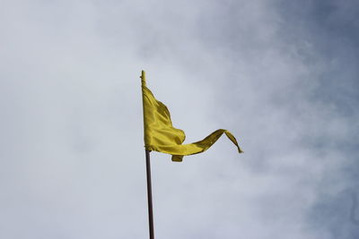 Low angle view of yellow flag against sky