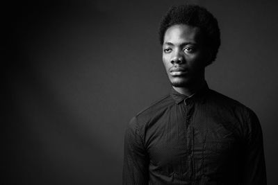 Portrait of young man against black background