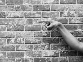 Person hand against brick wall