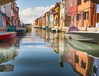 Boats moored in canal by buildings in city