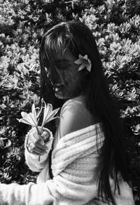 Close-up of happy woman holding flowers against trees