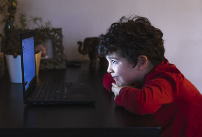 Side view of boy using mobile phone at table