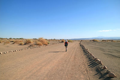 Rear view of woman on desert against clear sky