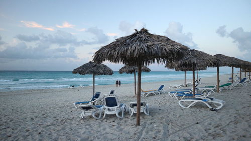 Deck chairs on beach against sky