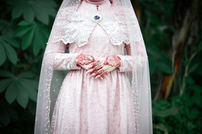 Close-up of woman standing by pink dress