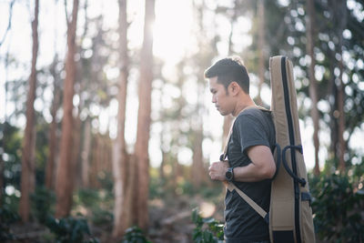 Side view of young man looking away in forest