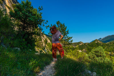 Rear view of man on mountain against clear blue sky