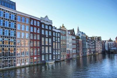 Canal in city against clear sky