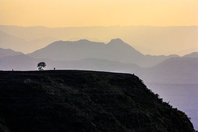 Silhouette people on mountain against sky during sunset