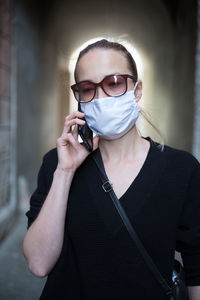 Portrait of a young woman standing against wall