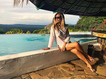 Full length of woman sitting on poolside