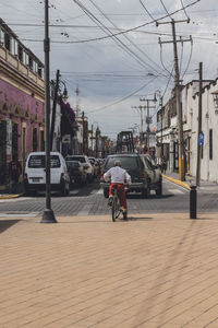 Rear view of man riding bicycle on street in city