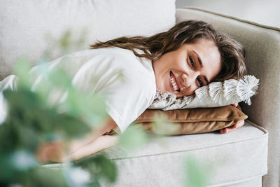 Portrait of young woman resting on sofa at home