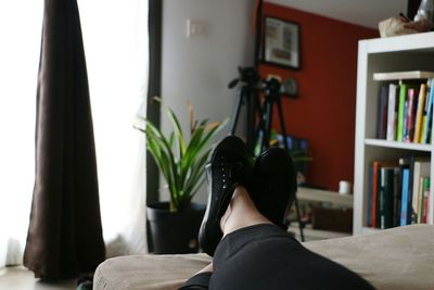 Low section of woman reading book at home