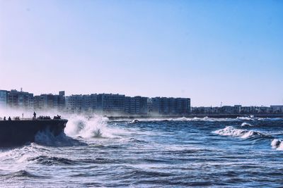 View of pier and sea in front of buildings against clear sky