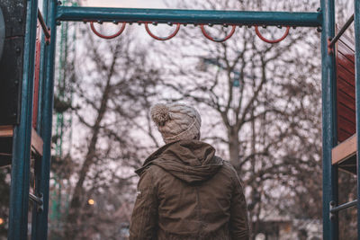 Rear view of man standing at park during winter