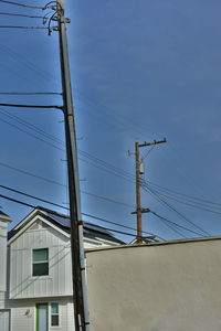 Low angle view of electricity pylons and buildings against sky