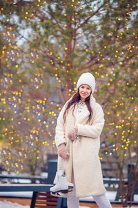 Portrait of smiling young woman standing by tree