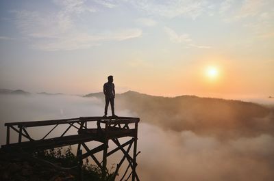 Silhouette of man standing on mountain at sunset