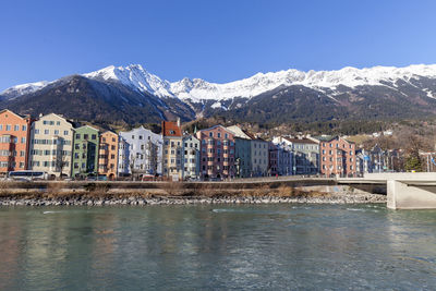 Buildings by snowcapped mountains against clear sky