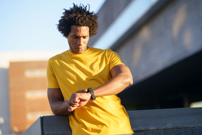 Young man holding yellow while sitting outdoors