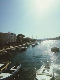 Boats moored at harbor against clear sky