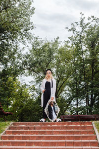 Full length portrait of young man against trees