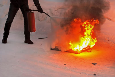 Low section of man extinguishing fire outdoors