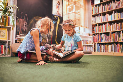 Two primary schoolgirls doing homework in school library. students learning from books