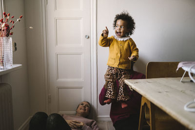 Father lifting smiling daughter at home