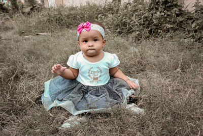 Portrait of cute baby girl sitting on land