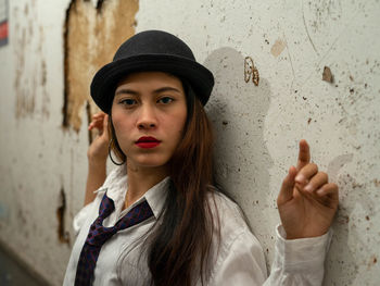 Young woman wearing shirt and tie standing against abandoned wall