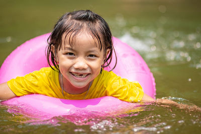 Portrait of smiling girl with inflatable ring swimming in lake