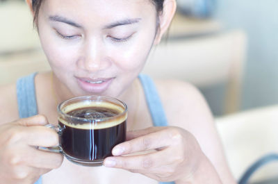 Close-up portrait of a smiling young woman holding drink